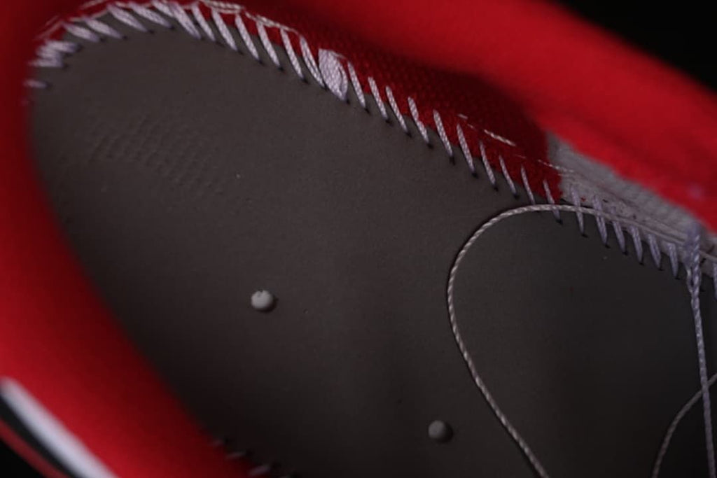 Close-up of dark panel stitching and small raised details on the sneaker.