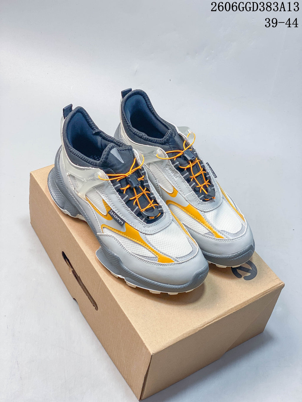 Pair of white and gray ECCO sneakers with orange accents and quick-lace cords, shown on a shoe box.