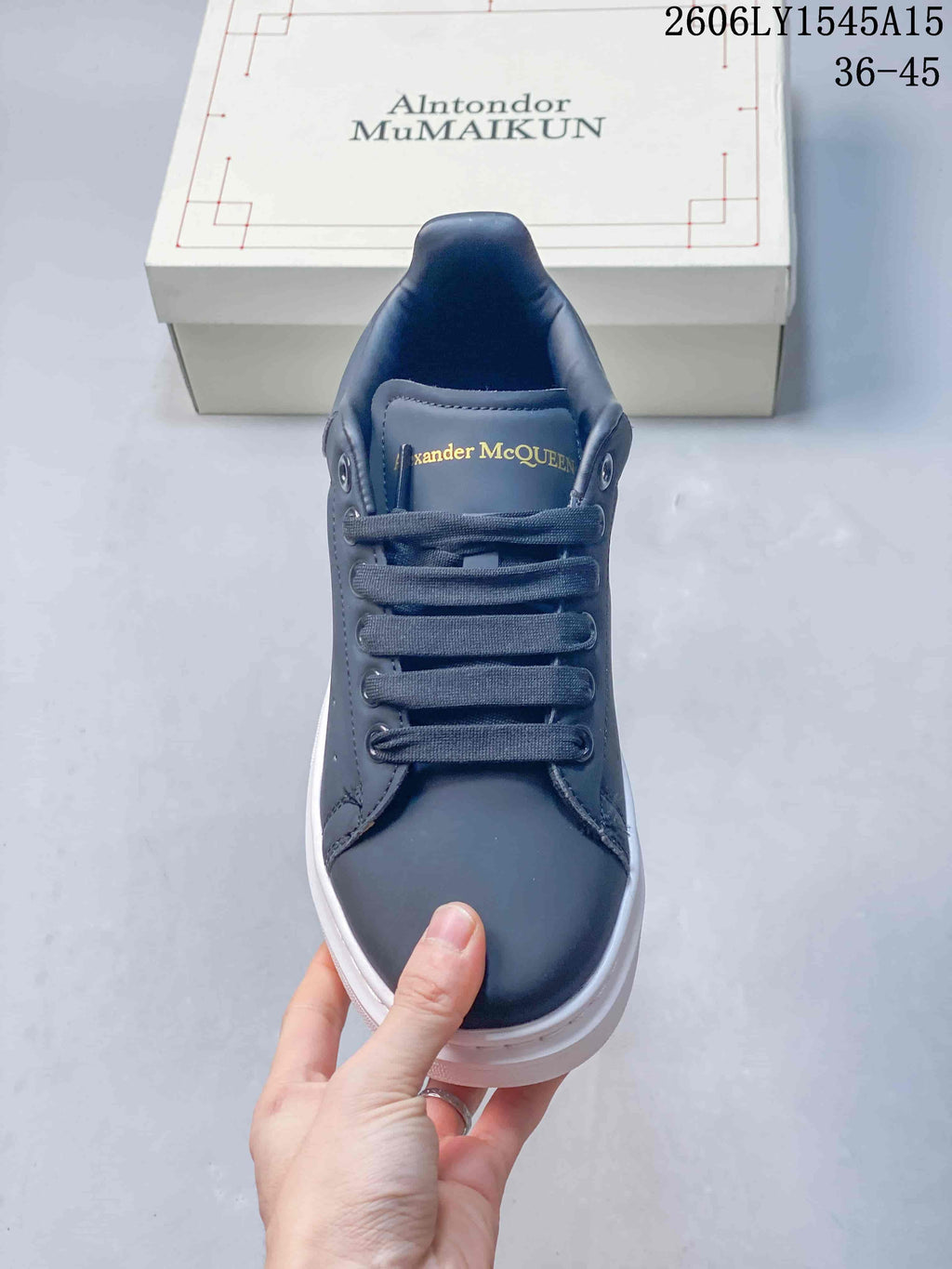 Front view of a navy lace-up sneaker with gold-tone tongue lettering.