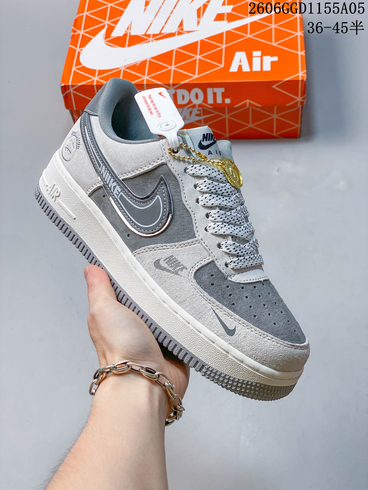 Angled side view of a grey and white Nike Air Force 1 sneaker with a hanging charm