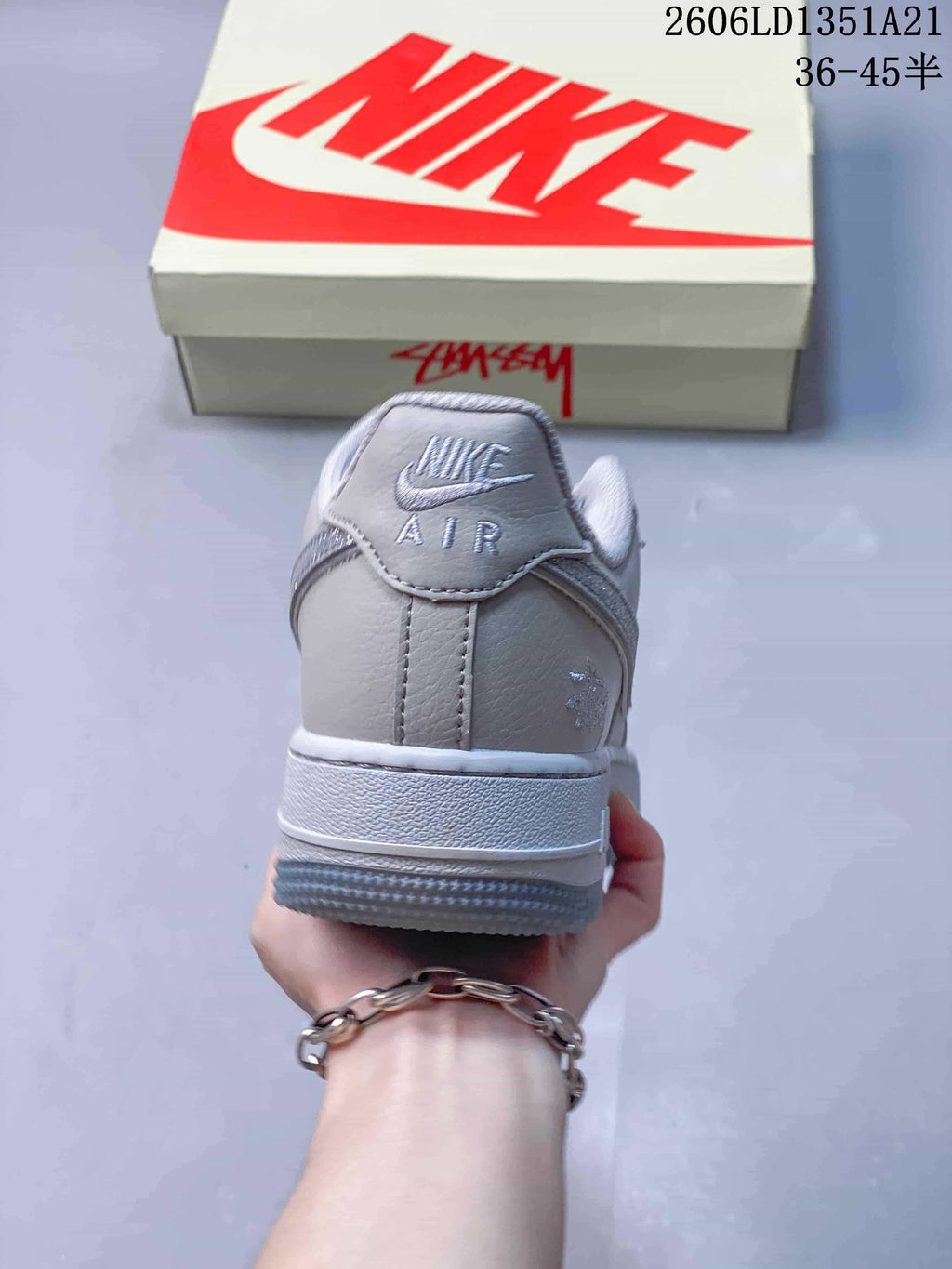 Rear view of a light gray Nike Air Force 1 with embroidered heel branding