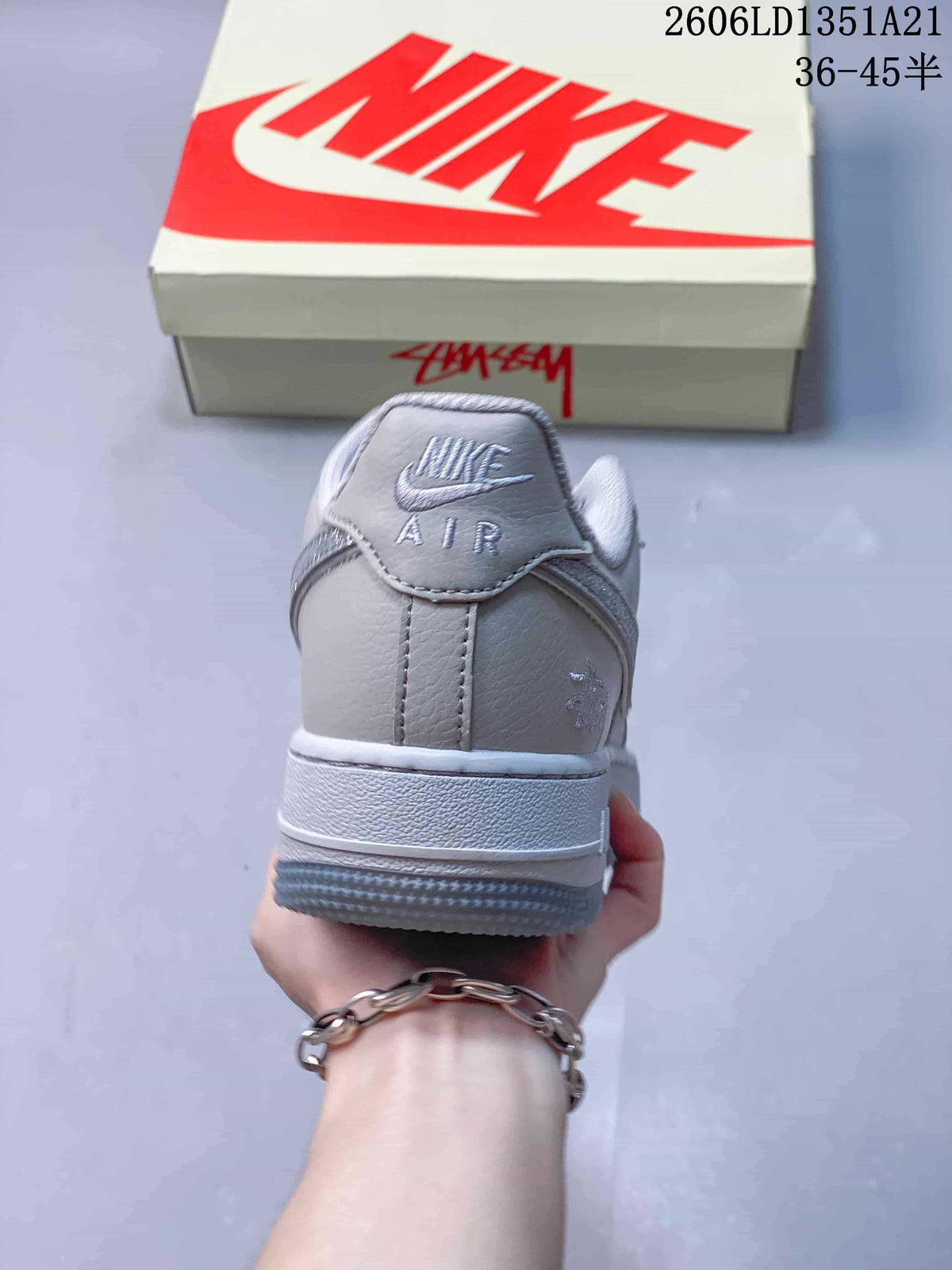 Rear view of a light gray Nike Air Force 1 with embroidered heel branding