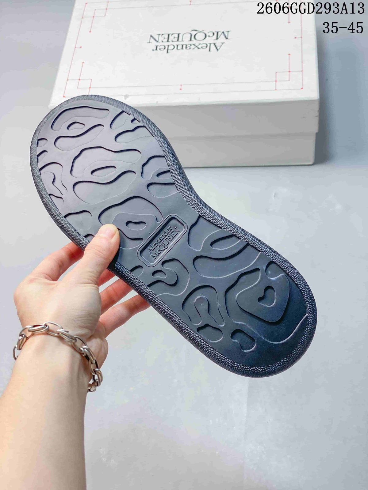 Underside of a dark charcoal sneaker showing its patterned tonal tread.