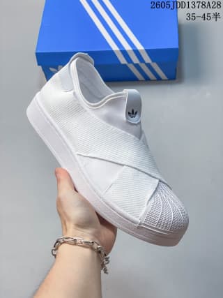 Side view of a white slip-on shoe with crossed straps and a textured shell toe.