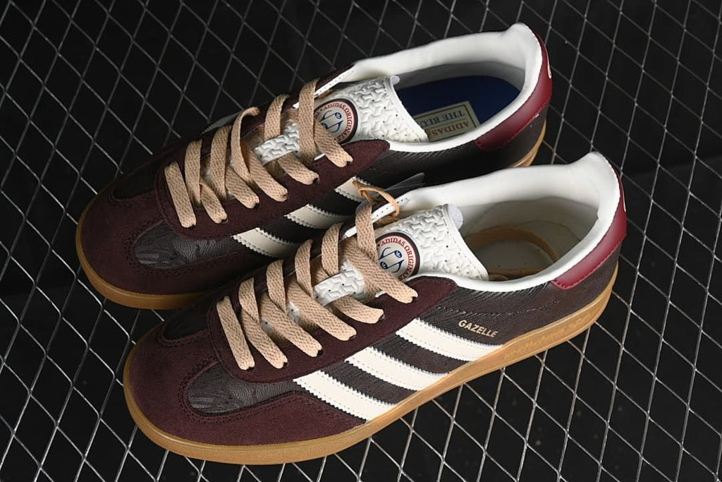 Pair of Gazelle Indoor sneakers with burgundy and dark brown panels, beige laces, and gum soles.