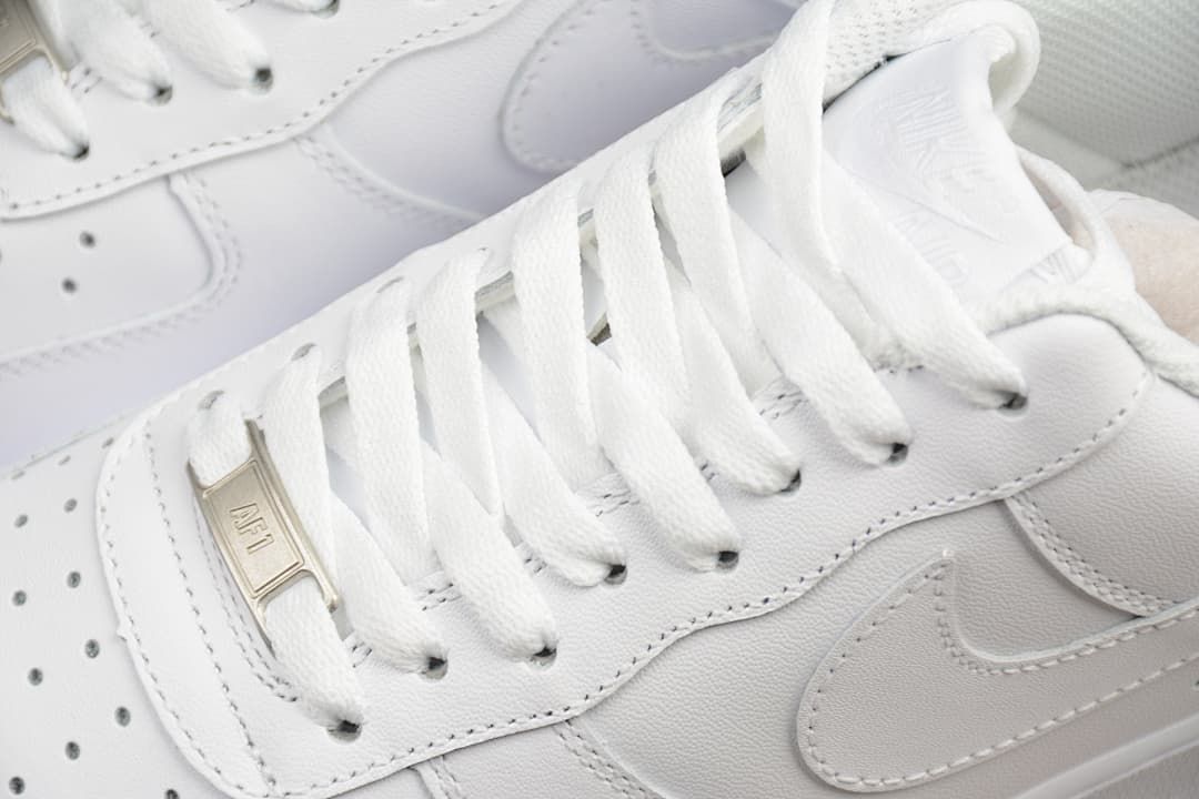 Close-up of white laces, metal lace tag and side Swoosh detail.