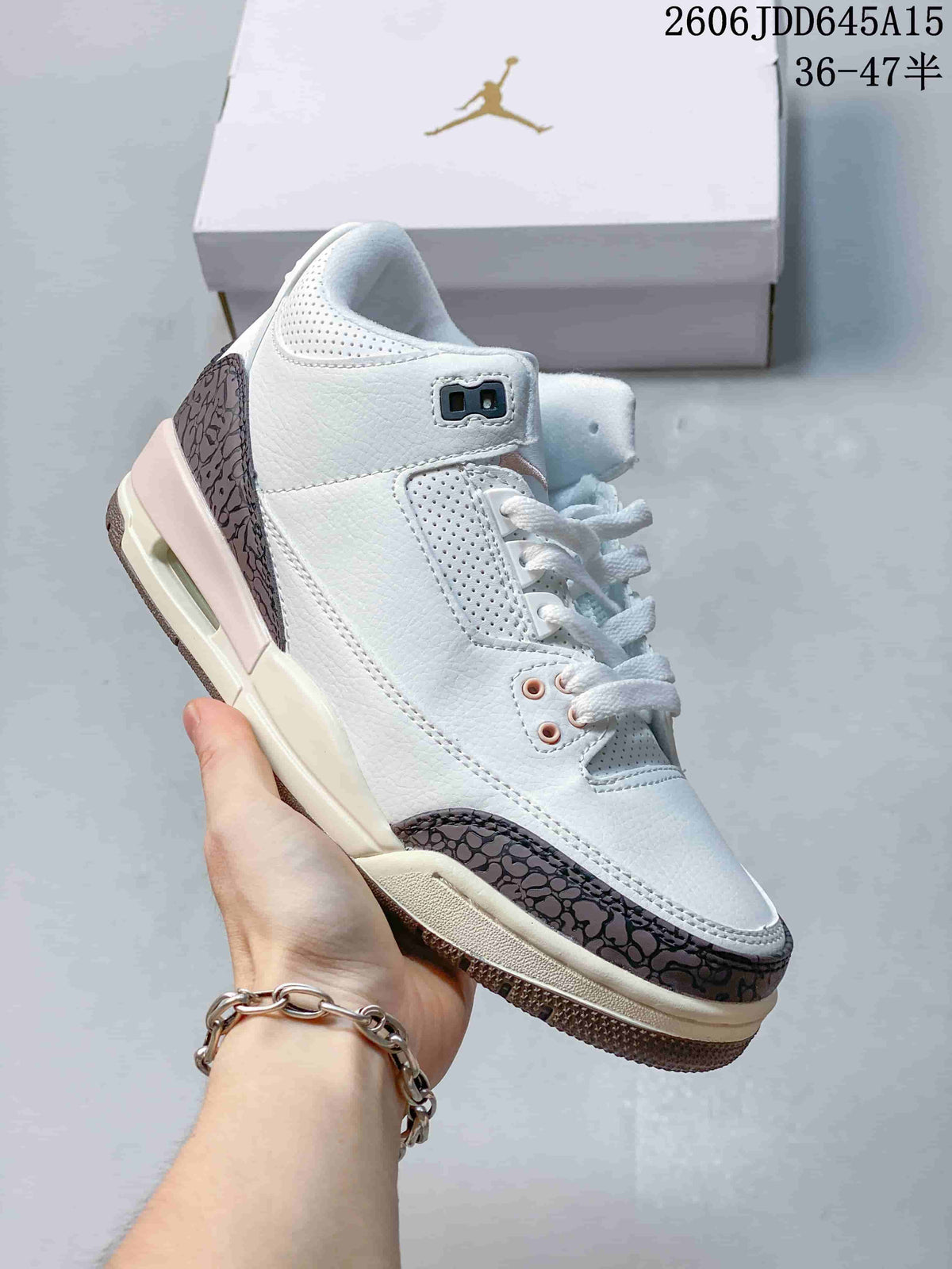 White low-top Jordan sneaker with dark patterned overlays and light-colored midsole.