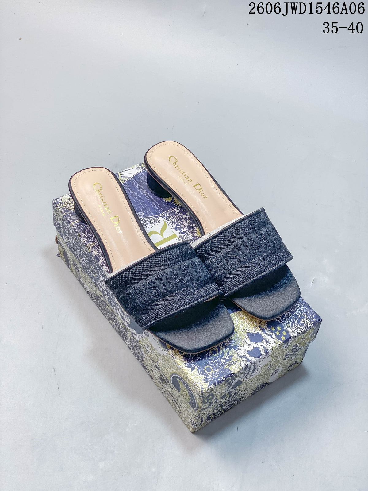 Pair of dark navy embroidered Dior Dway-style mule sandals with square toes, shown on a patterned box