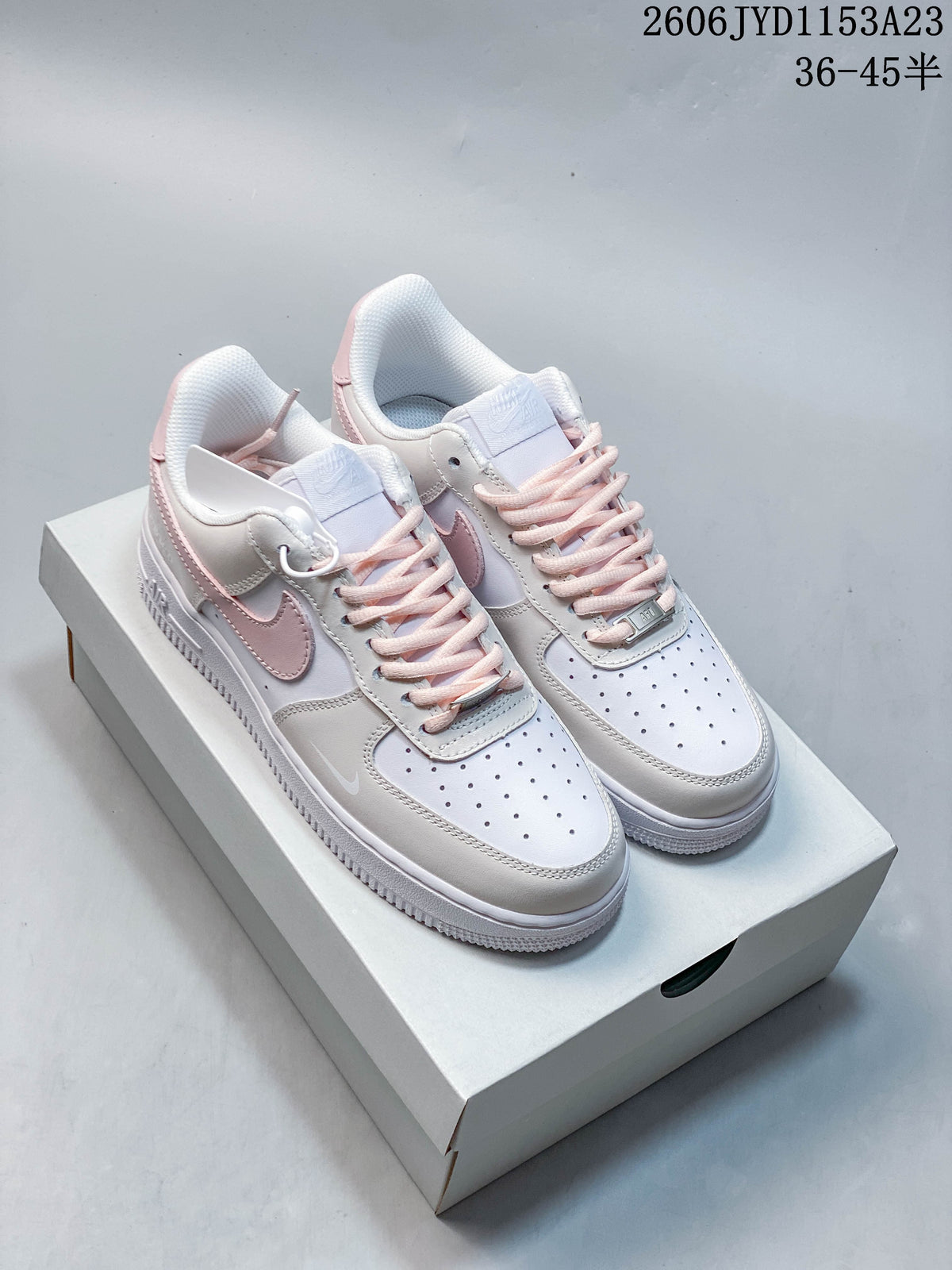 Pair of white and pale pink low-top sneakers shown from above on a shoe box