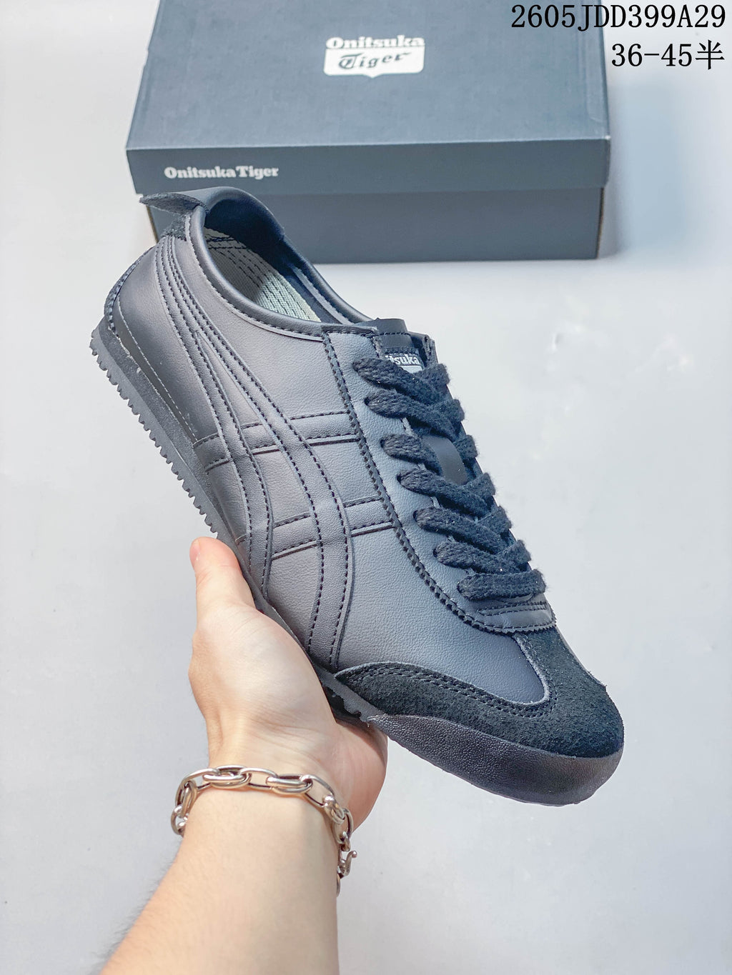 Angled side view of a gray Onitsuka Tiger low-top sneaker with dark toe overlay and side stripes.