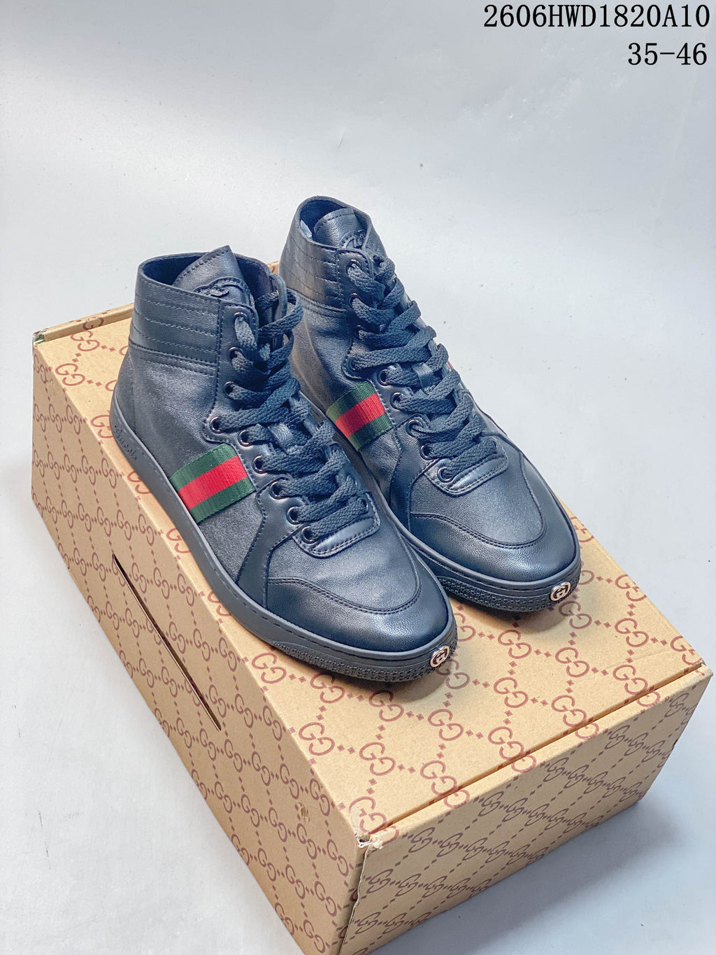 Pair of dark gray high-top lace-up sneakers with green-and-red side stripes, shown on a patterned box.