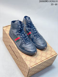 Pair of dark gray high-top lace-up sneakers with green-and-red side stripes, shown on a patterned box.
