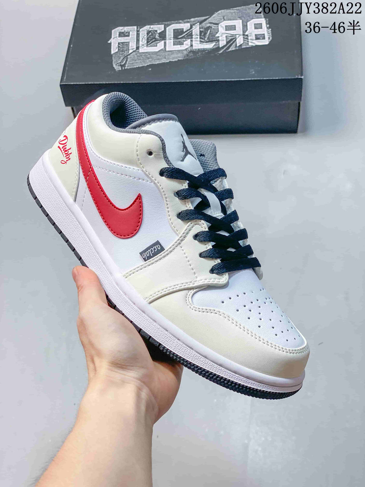White low-top sneaker with a red Swoosh, red heel detail, and dark laces.
