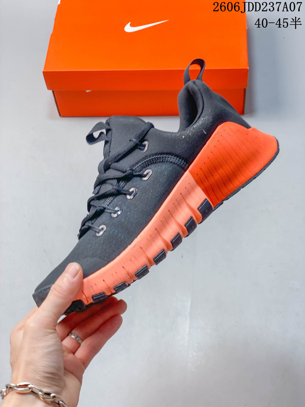 Side view of the dark lace-up shoe with orange sole and heel details