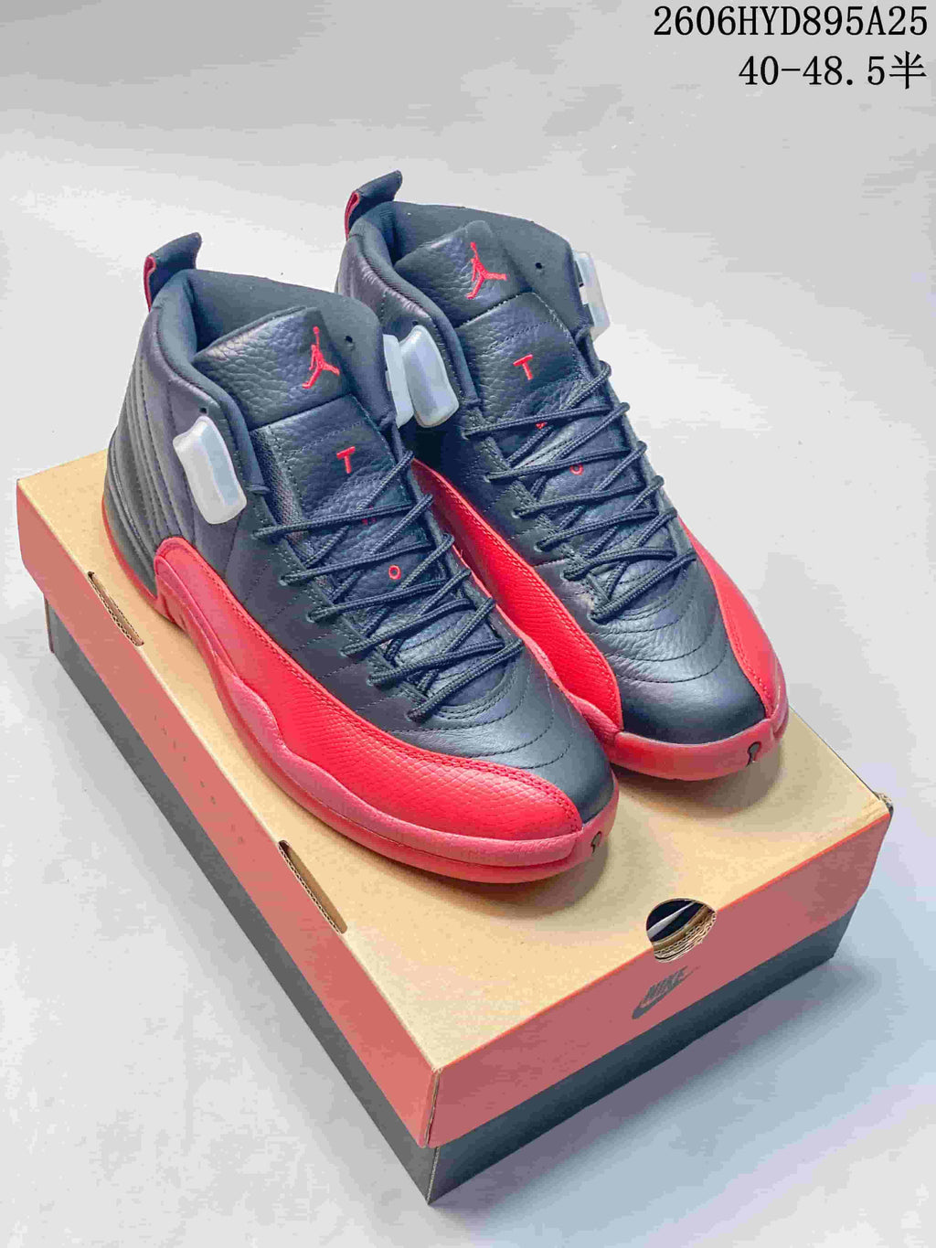 Black and red Jordan Air Jordan 12 high-top shoes displayed on a shoe box; image includes a printed size range.