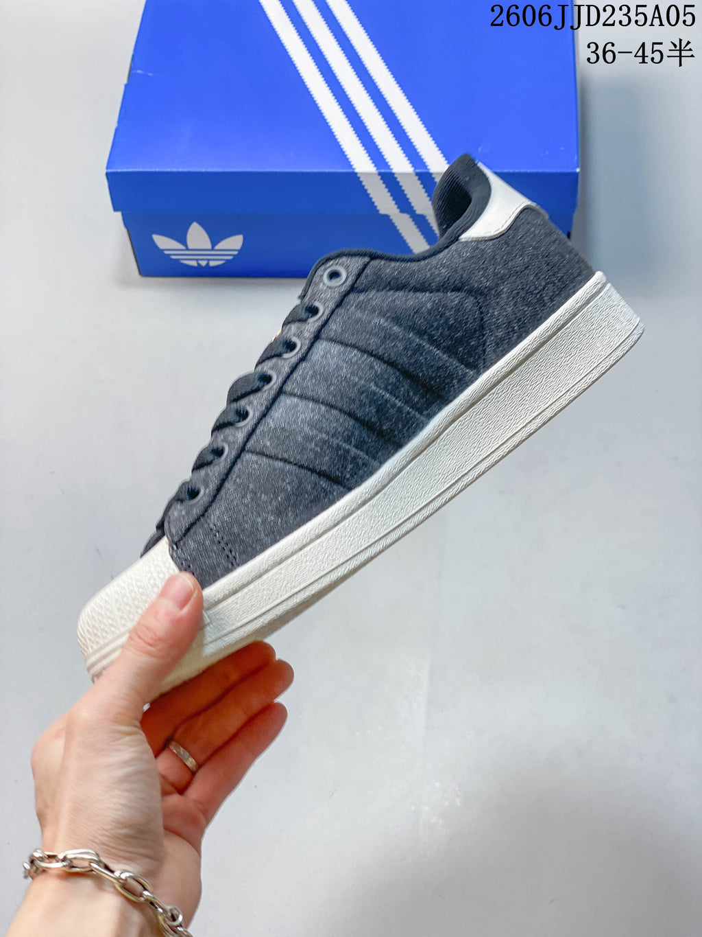 Side profile of a charcoal gray low-top sneaker with three side stripes and a white sole