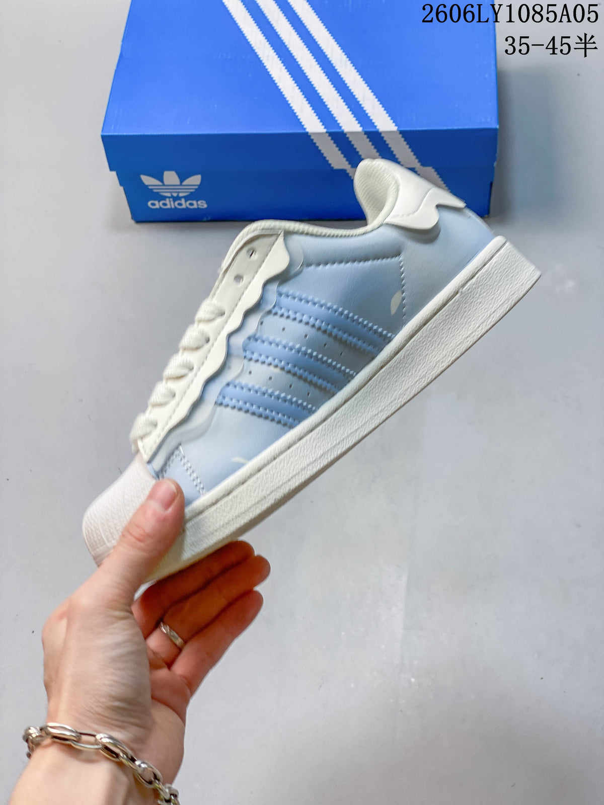 Side profile showing pale blue panels, three stripes, and off-white sole