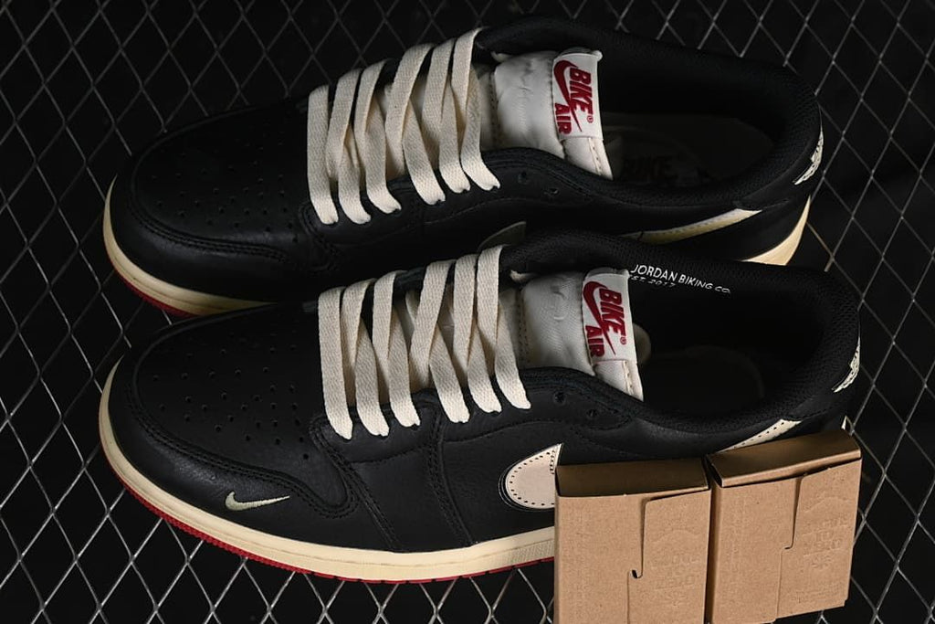 Pair of black low-top sneakers with cream laces and small kraft-colored boxes