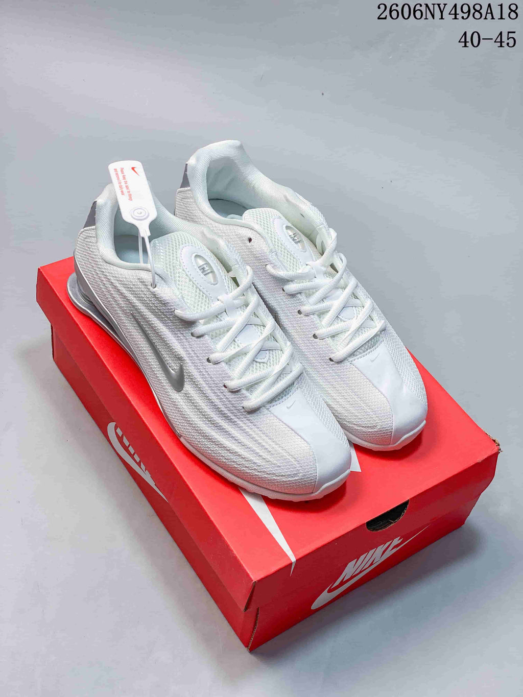 Pair of white and silver Nike Shox TL sneakers displayed on a red shoebox