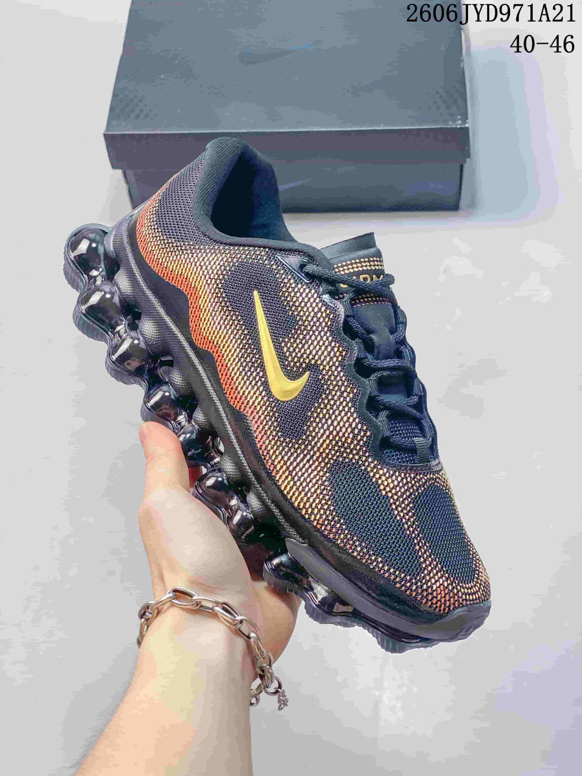 Side view of a patterned navy, red and gold Nike Air Liquid Max shoe with a segmented bubble-like sole; image displays a size range.