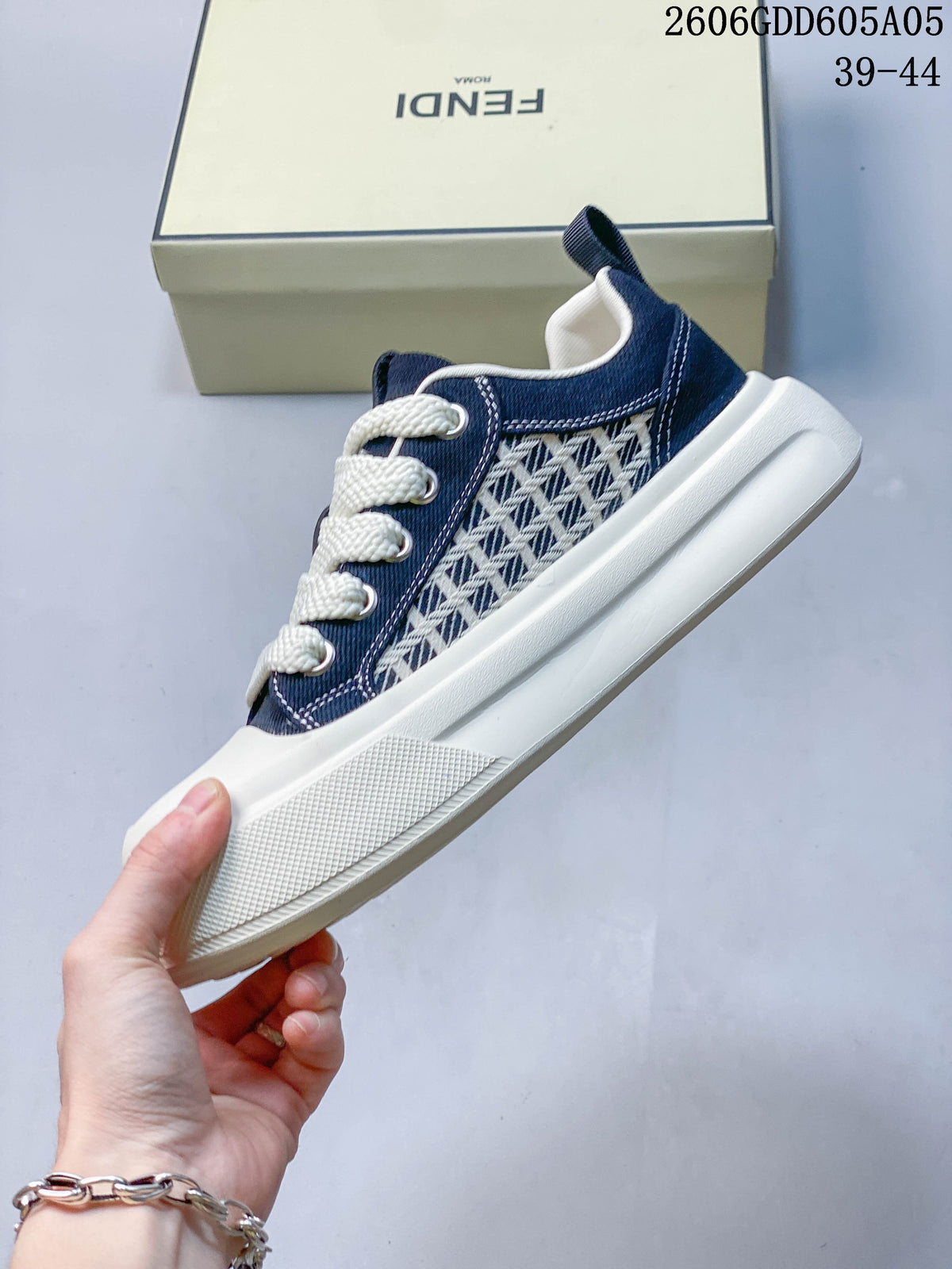 Side view of a navy low-top sneaker with a geometric-patterned panel, cream laces, and thick light-colored sole.