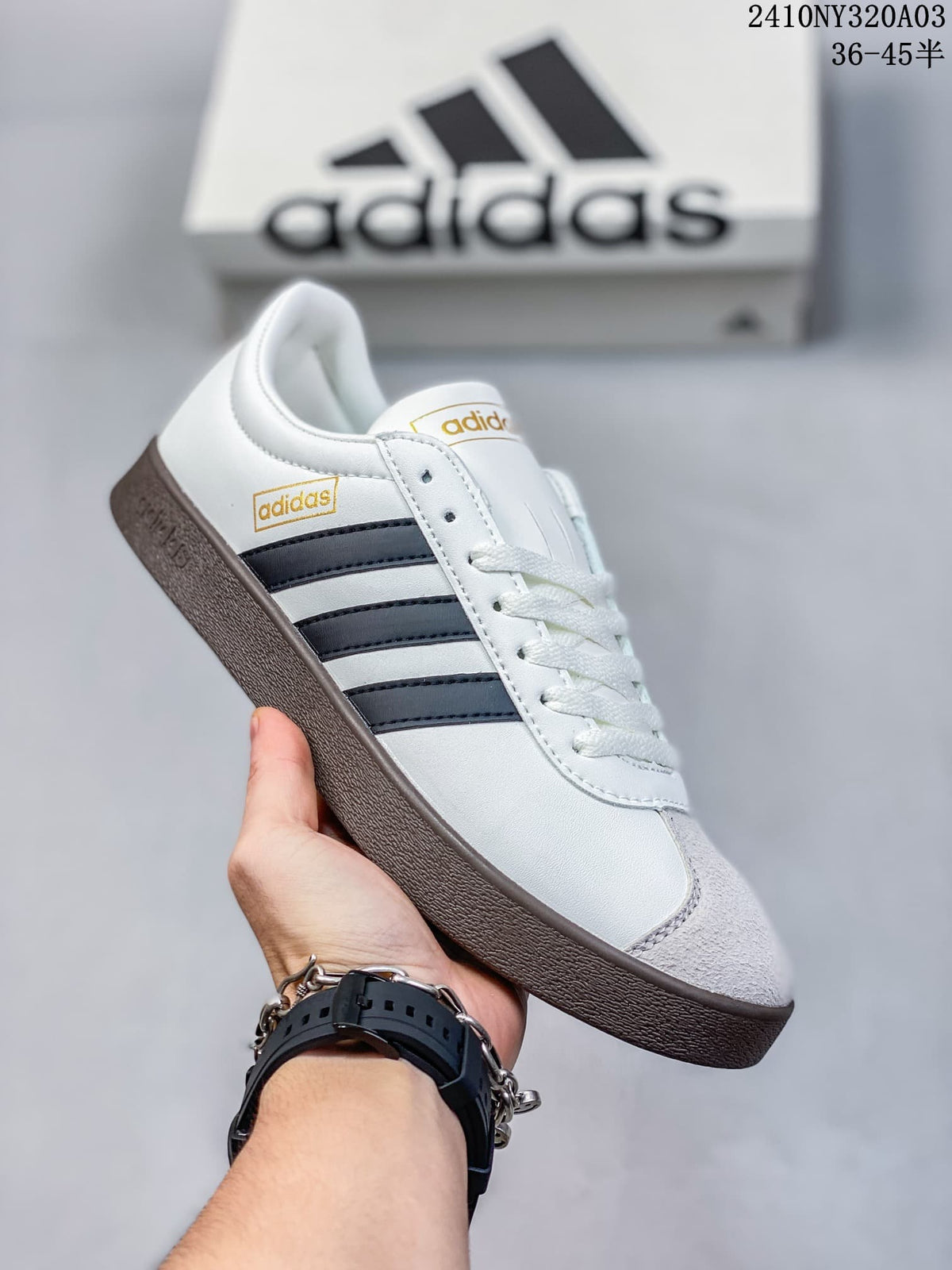 Angled side view of the white sneaker with navy stripes, light gray toe accent, and dark brown outsole