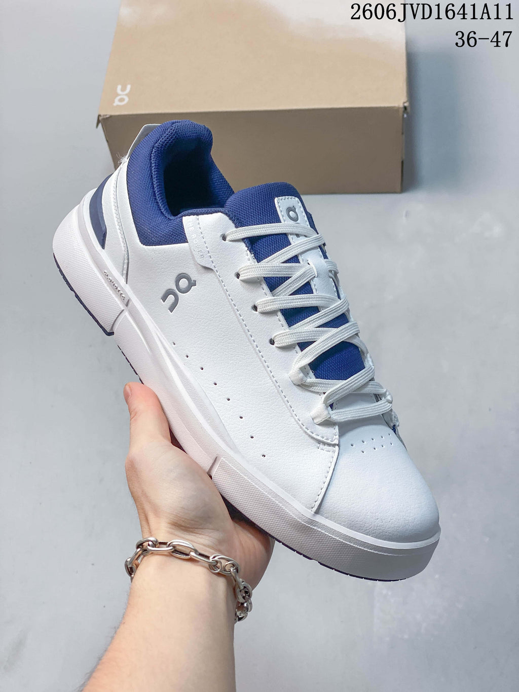 Angled view of a white and blue On sneaker showing its side logo and low-top profile.