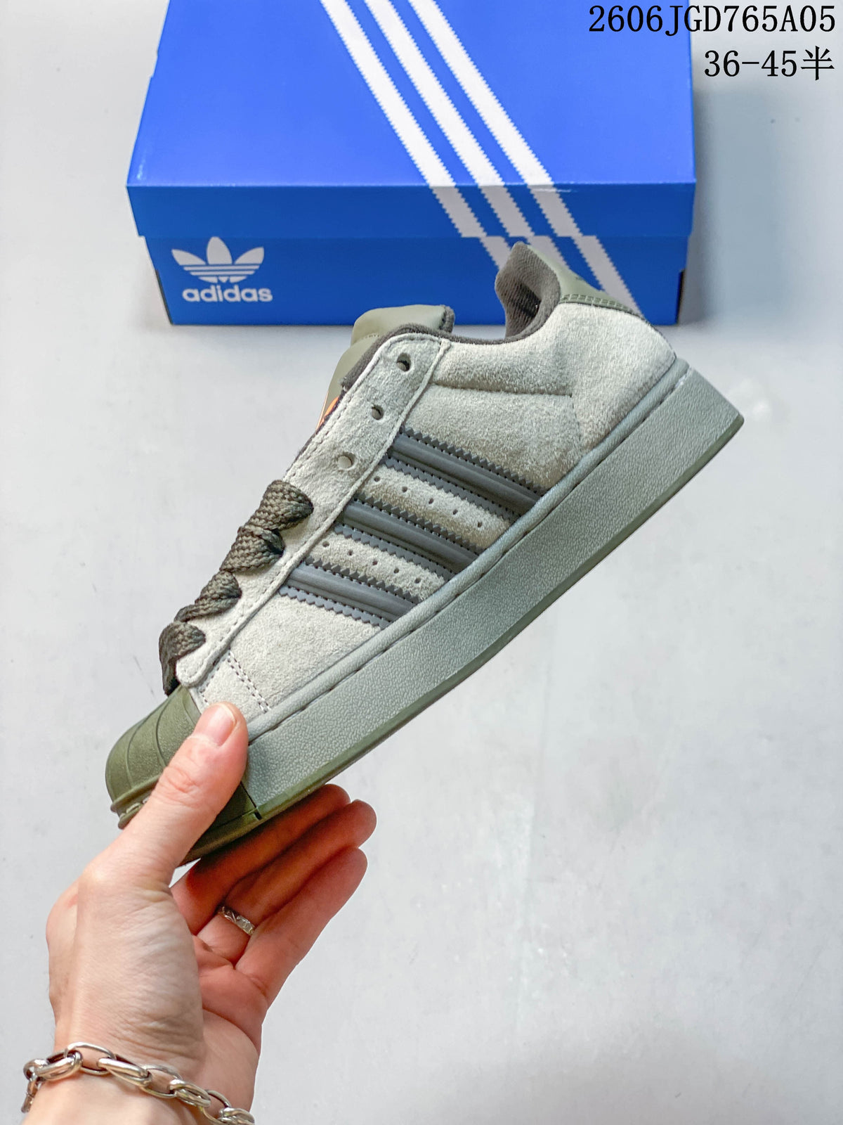 Side profile of an olive and gray Adidas Originals Superstar XLG sneaker with three stripes and a shell toe