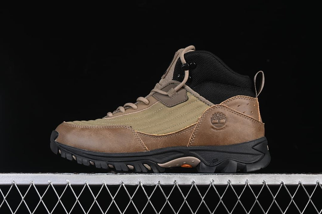Side view of an olive and brown mid-height Timberland lace-up boot with a black lugged sole.