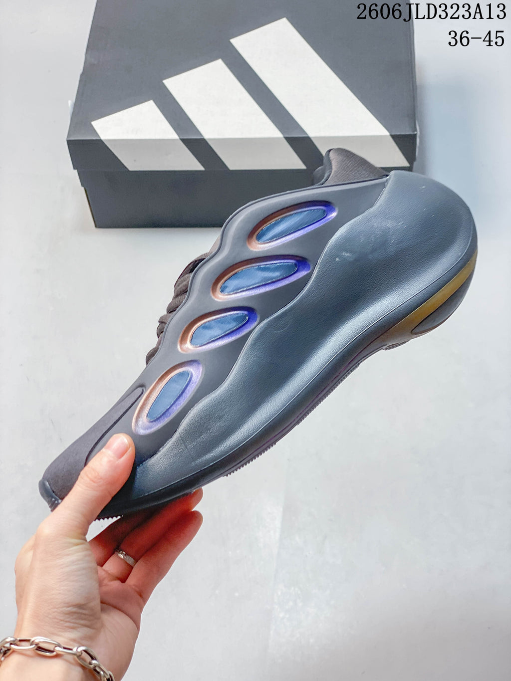 Side profile of the gray sneaker with sculpted panels and iridescent accents.
