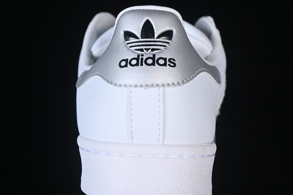 Rear view of the white sneaker with a silver heel panel and adidas trefoil branding