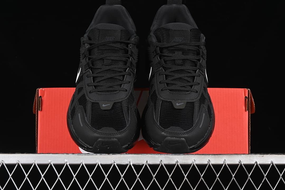 Front view of the pair of black sneakers resting on the shoebox.