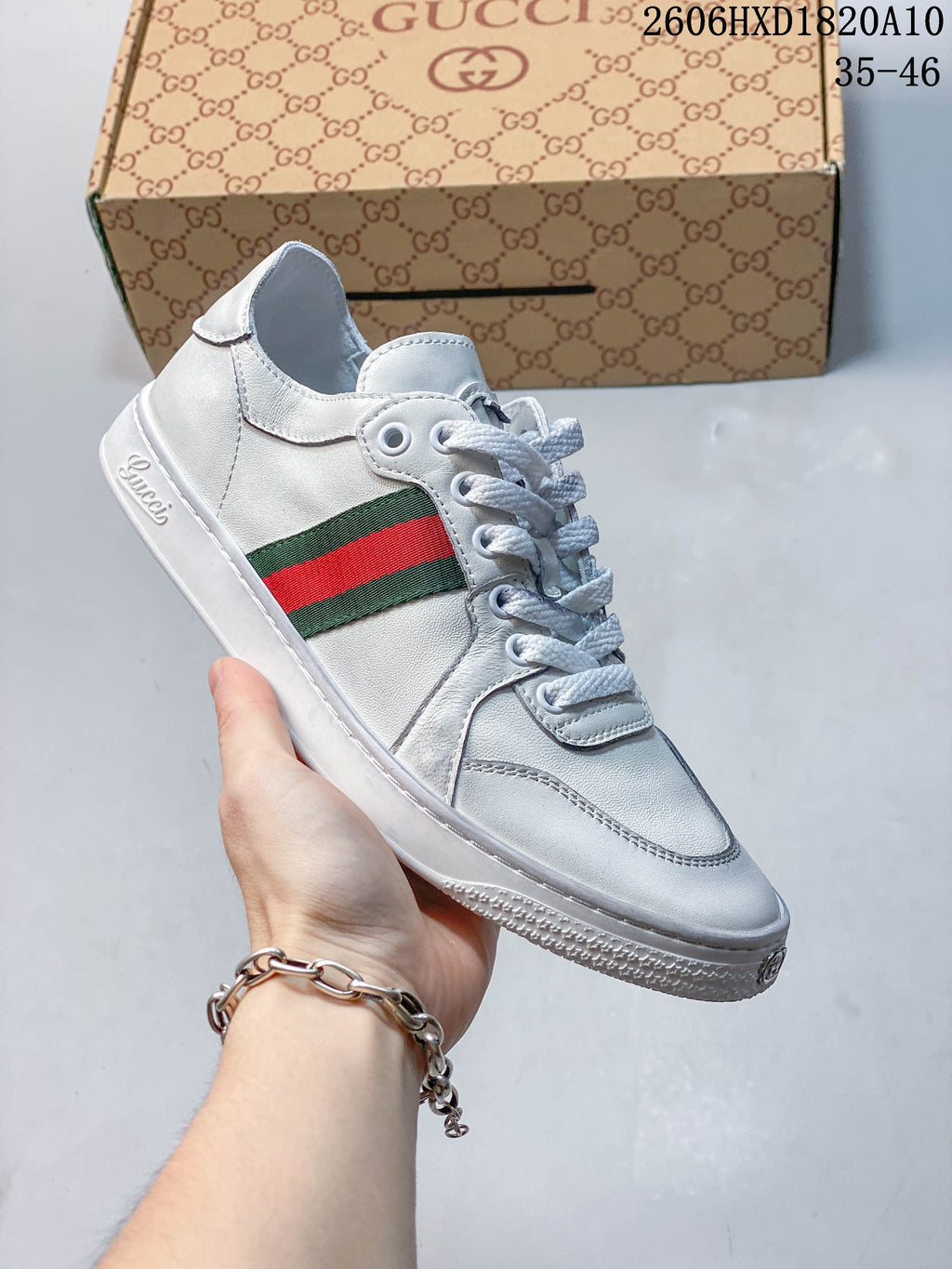 Angled side view of a white low-top sneaker with a green-and-red stripe and lace-up closure.