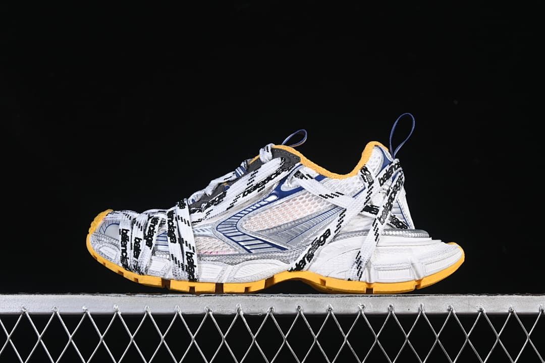 Side view of white Balenciaga 3XL sneakers with logo laces and orange outsole