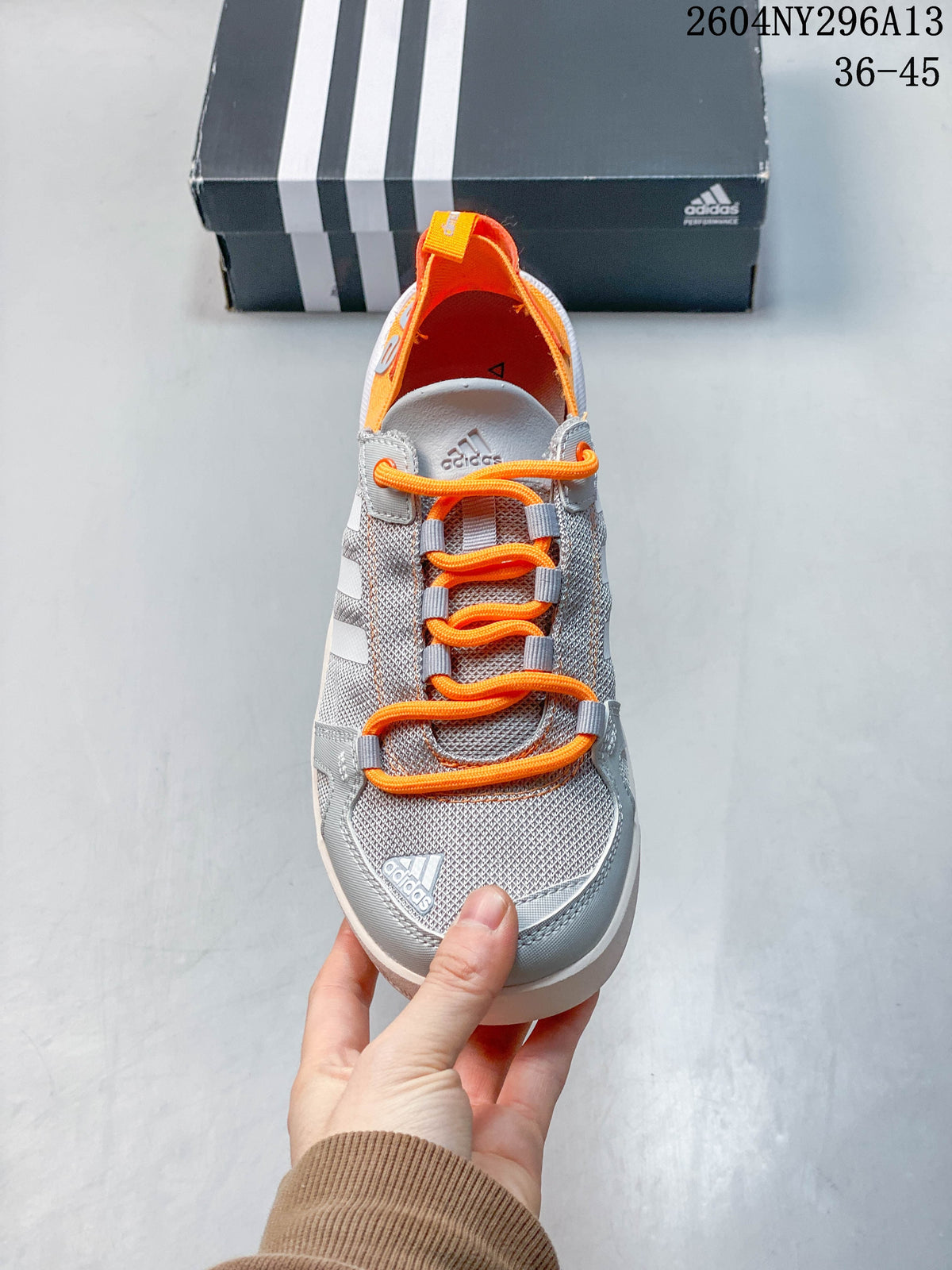 Front view highlighting the orange laces and grey mesh-style upper.