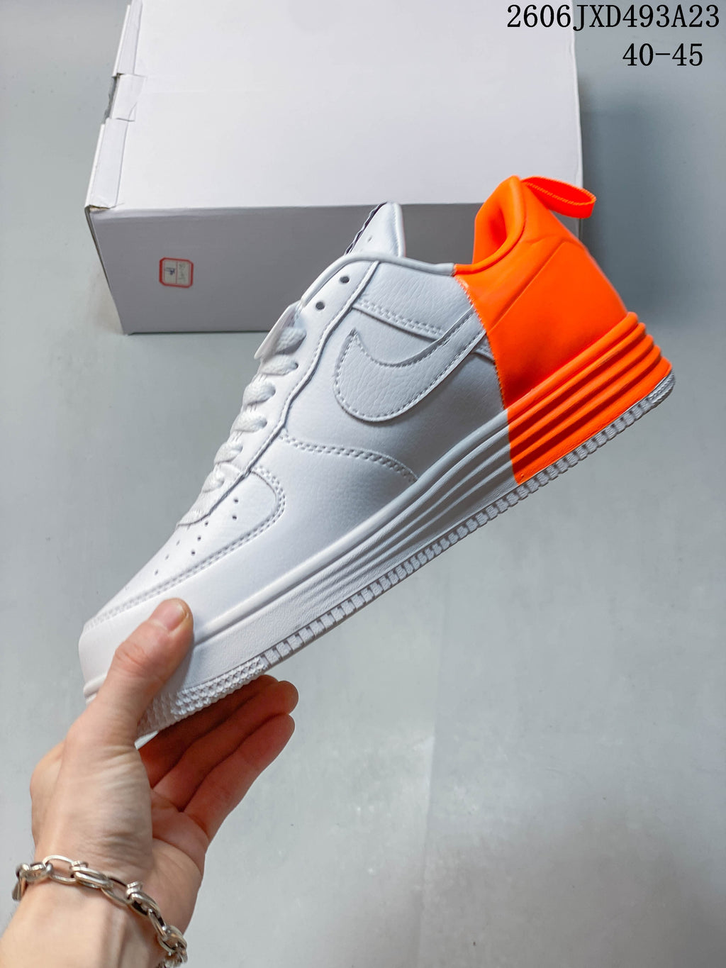 Side profile of a white low-top sneaker with an orange heel section