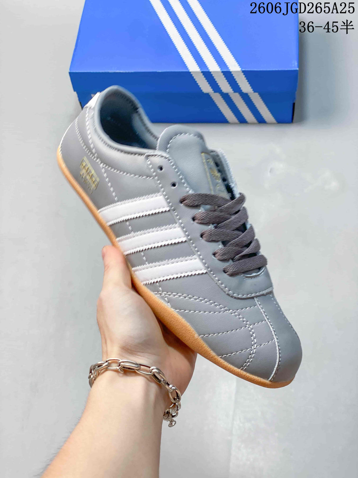 Side view of a gray adidas Originals Tokyo sneaker with white stripes and gum-colored sole