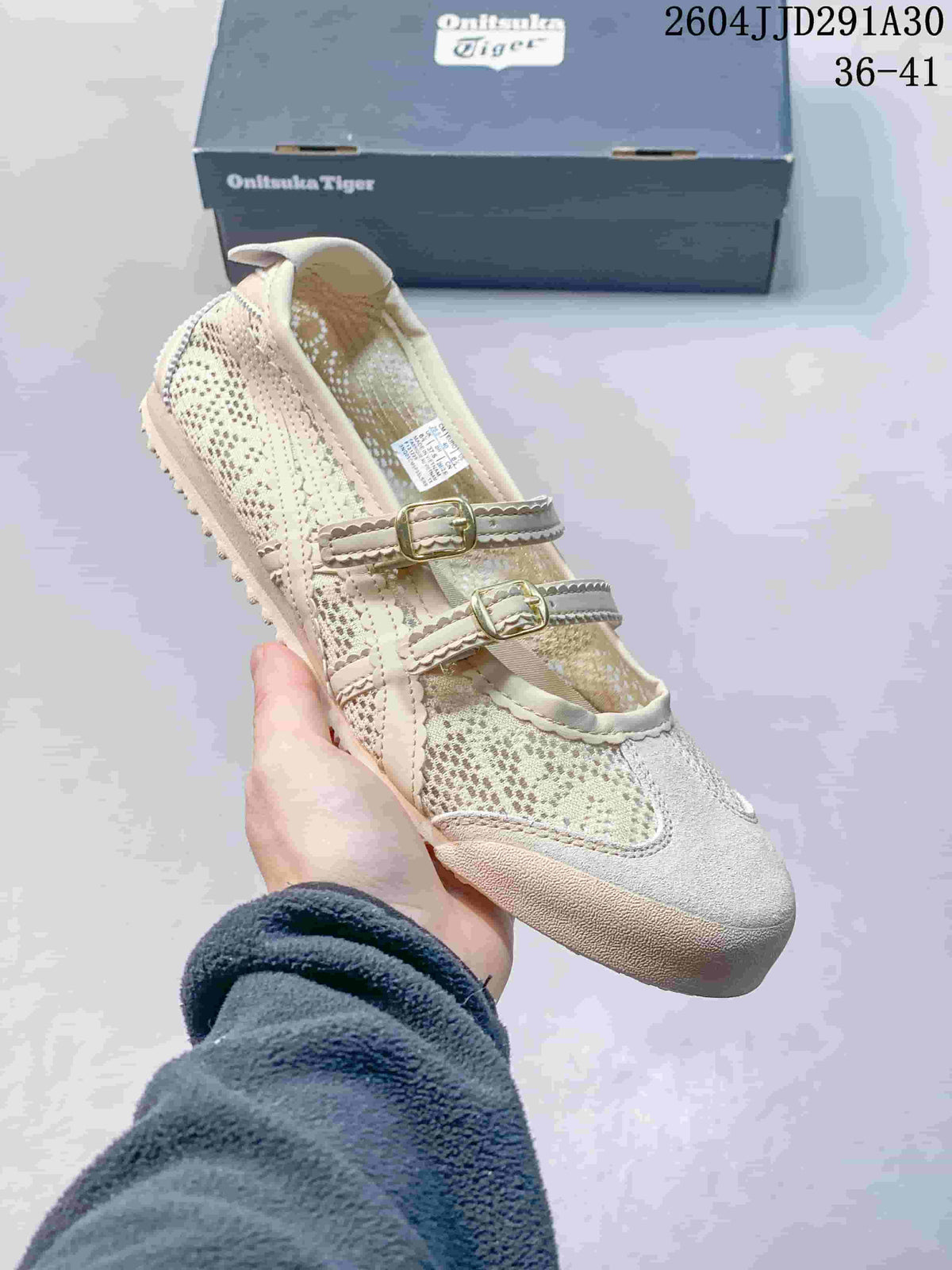Light-colored Mary Jane-style shoe with two buckle straps, shown beside an ASICS-branded box