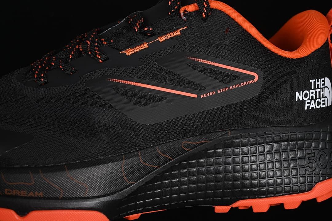 Close-up of the black and orange lace-up upper and side branding.