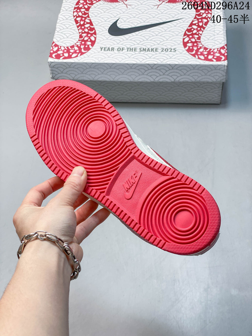 Red outsole with circular tread beside a Year of the Snake 2025 shoe box