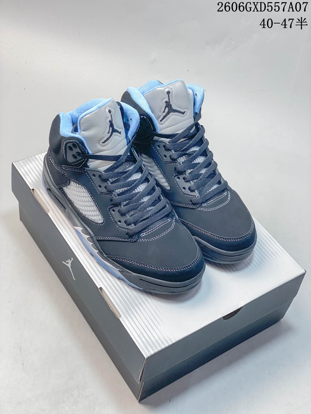 Pair of dark gray and navy Jordan Air Jordan 5 high-top sneakers with light blue accents, shown on a shoebox.