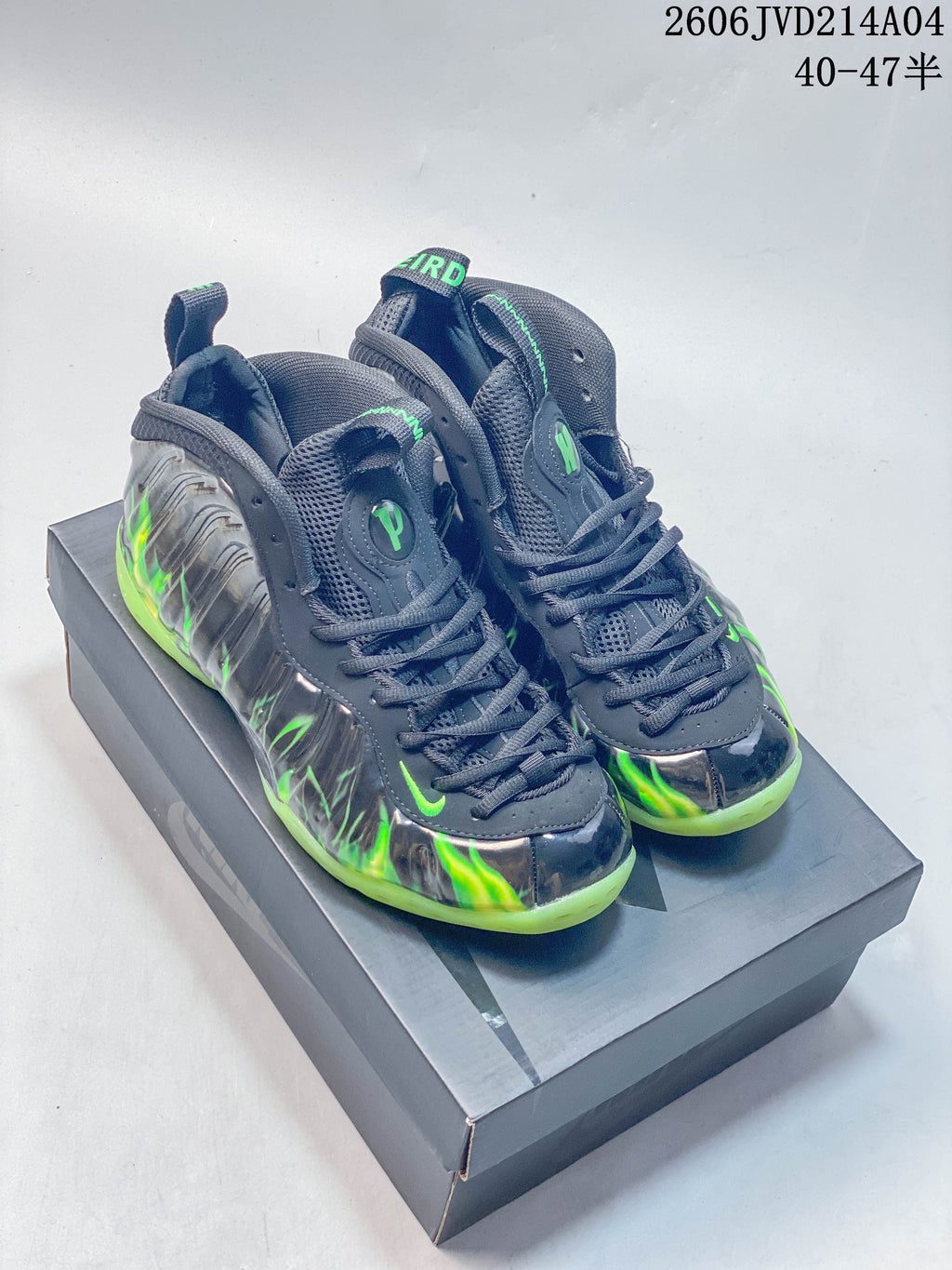 Pair of gray Nike Air Foamposite Pro high-top basketball shoes with green accents, shown on a shoebox.