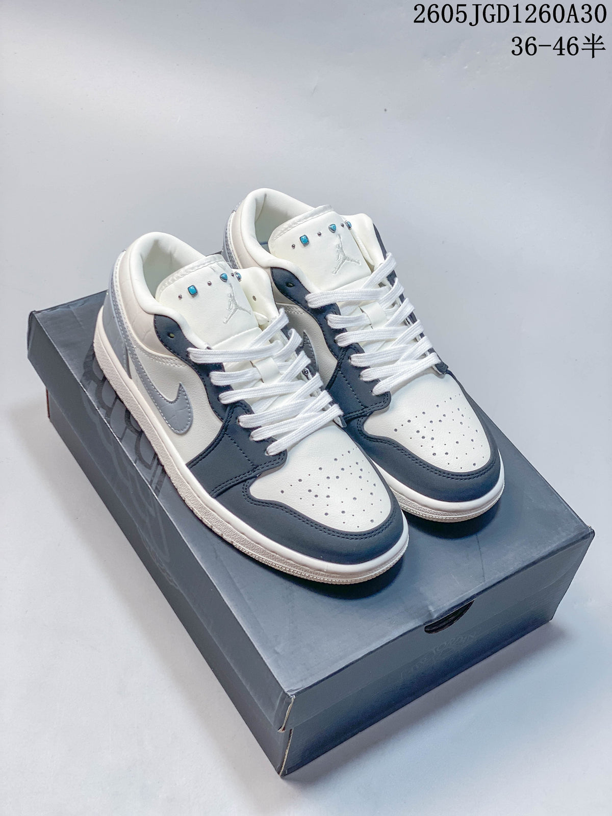 Pair of white, dark blue, and gray Air Jordan 1 Low sneakers on a shoebox