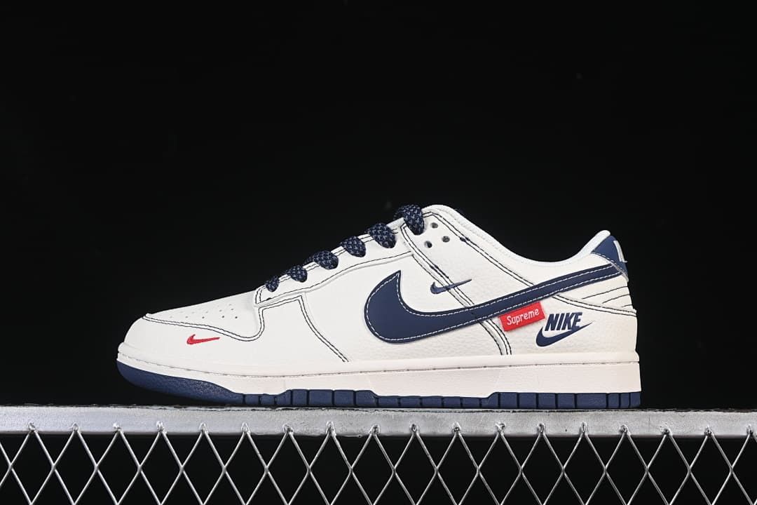 Side view of a white and navy Nike SB Dunk Low-style sneaker with red details
