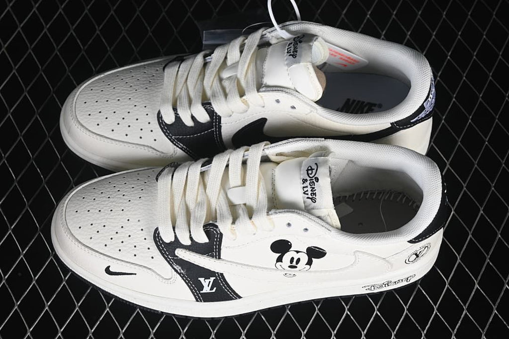Top view of a pair of white and black low-top sneakers with perforated toe panels, lace-up fronts, and Mickey Mouse graphics.