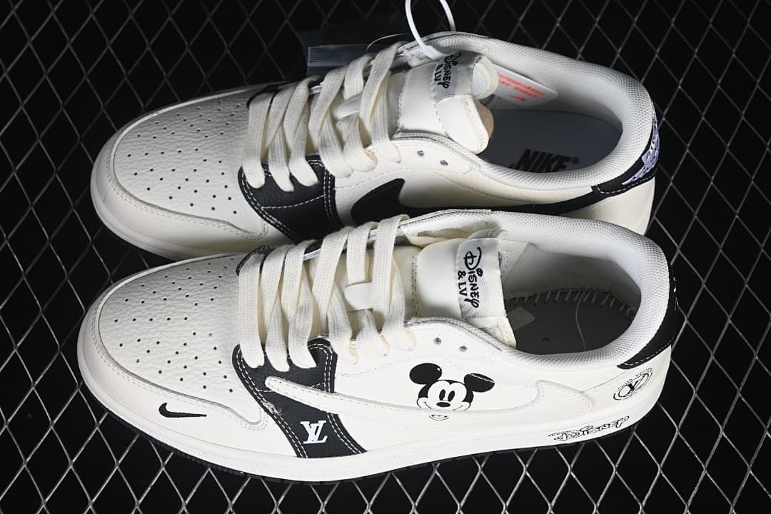 Top view of a pair of white and black low-top sneakers with perforated toe panels, lace-up fronts, and Mickey Mouse graphics.