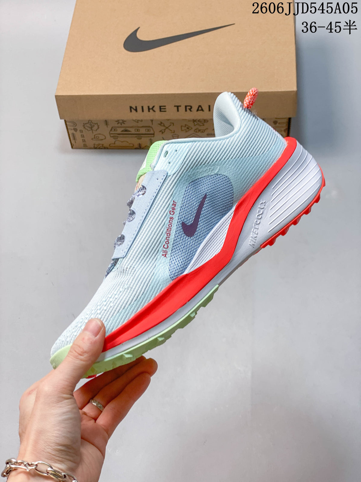 Side view of the light blue Nike Pegasus Trail 6 shoe with a white Swoosh and bright red-orange midsole accent.