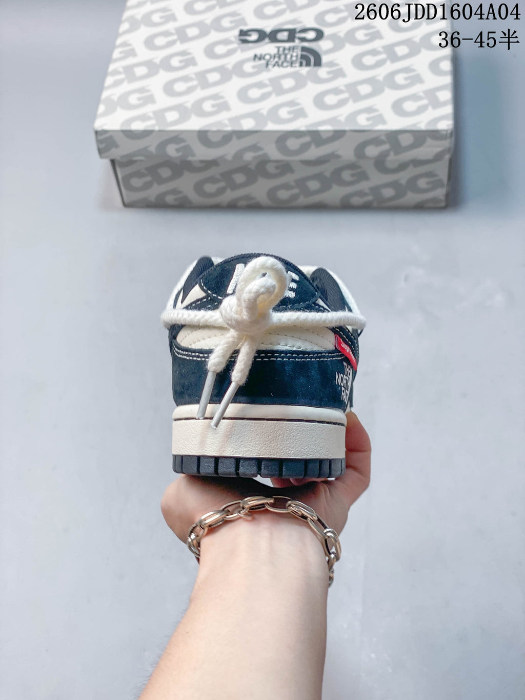 Rear view of a navy and off-white low-top sneaker with rope-style laces tied at the heel.