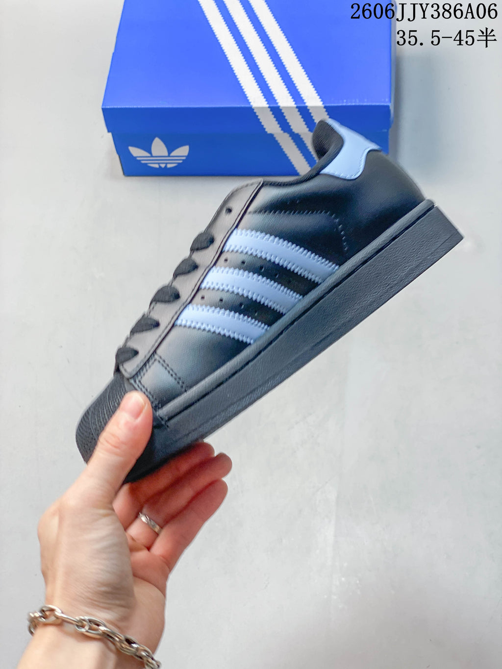 Side view of a charcoal adidas Superstar 2 sneaker with pale blue stripes