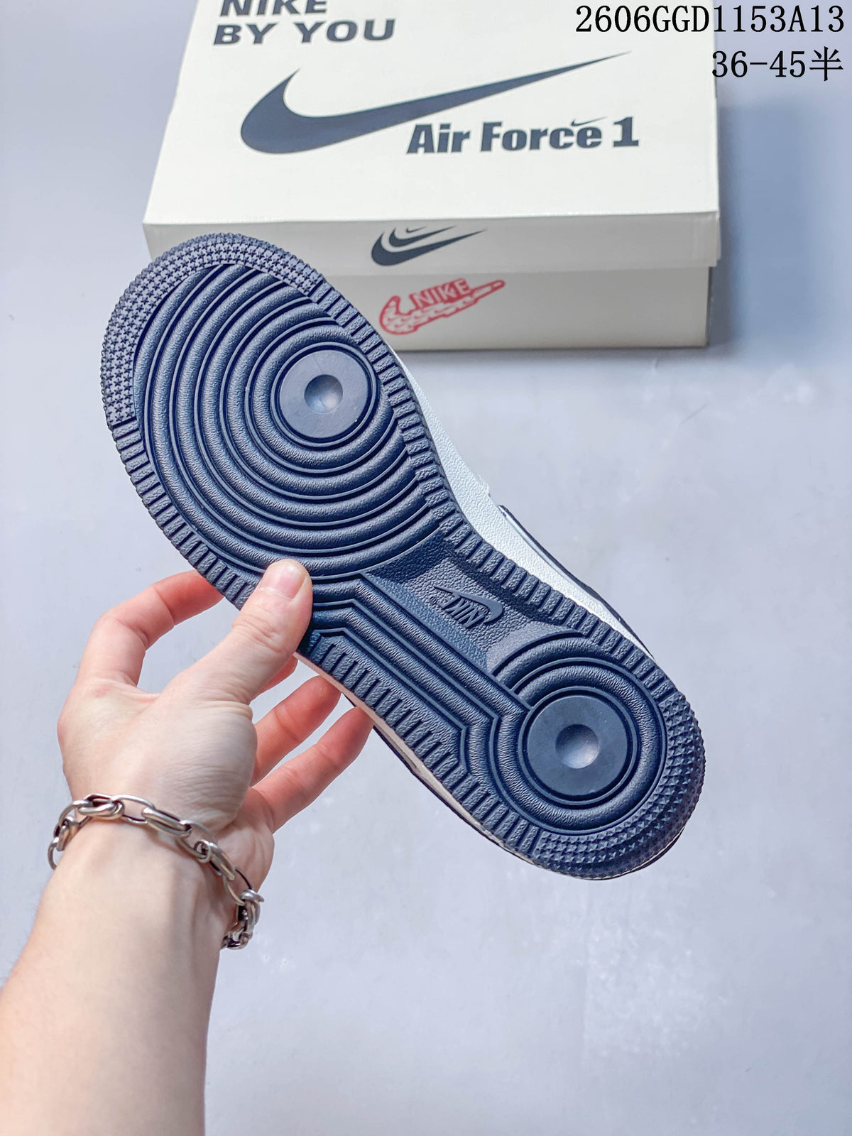 Navy rubber outsole of the Air Force 1 sneaker with its shoe box in the background